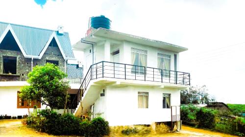 a white house with a balcony on top of it at Lotus View Home in Nuwara Eliya