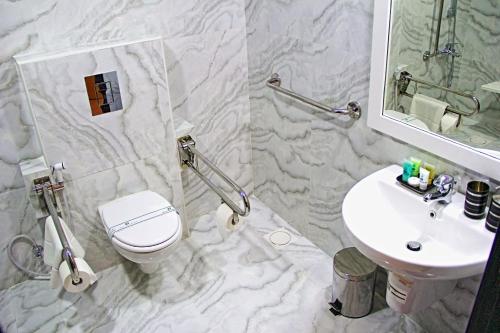 ein Badezimmer mit einem weißen WC und einem Waschbecken in der Unterkunft Bahrain International Hotel in Manama