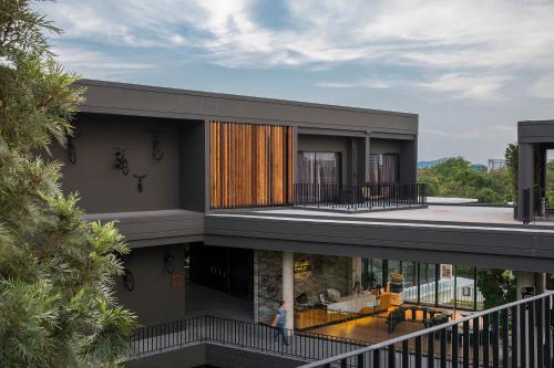a house with a balcony with a woman walking in front of it at Wheeler Bed &Bike in Bangsaen