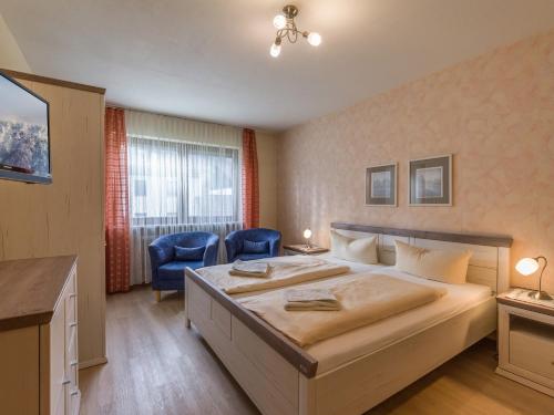 - une chambre avec un grand lit et deux chaises bleues dans l'établissement FerienwohnanlageOberaudorf B5 mit Hallenbad und Sauna, à Oberaudorf