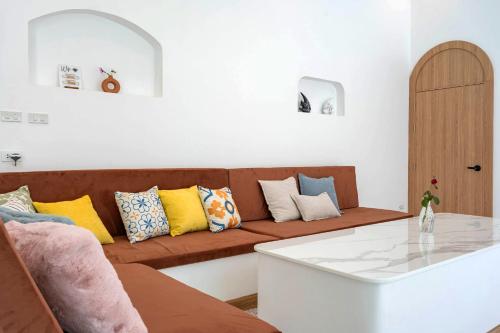 a living room with a brown couch with colorful pillows at Downtown Oasis 芭提雅市中心独栋泳池别墅 A 5卧6卫 KTV BBQ 芭提雅海滩步行街500m in Pattaya South