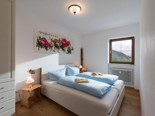 a bedroom with a bed with blue sheets and a window at Erdgeschosswohnung 8 im Bergschlössl in Oberaudorf