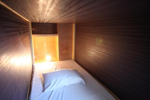a small bed with a white pillow in a room at Base Inn Komagome Tokyo in Tokyo