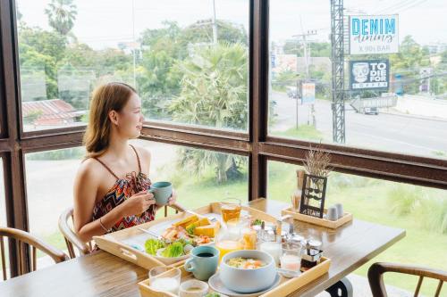 a woman sitting at a table with a tray of food at Wheeler Bed &Bike in Bangsaen