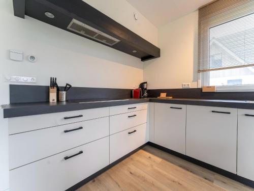 une cuisine blanche avec des armoires blanches et une fenêtre dans l'établissement Serene Holiday Home in De Koog Texel with Sauna, à Westermient