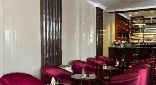 a restaurant with red chairs and tables and a bar at Sindoro Hotel Cilacap By Conary in Cilacap