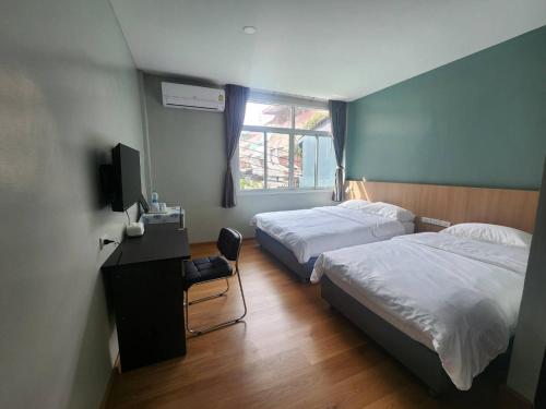 a bedroom with two beds and a desk and a television at Wan Residence Ratchatewi in Bangkok