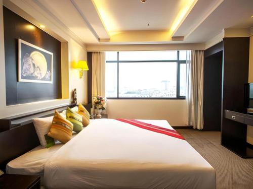une chambre d'hôtel avec un grand lit et une fenêtre dans l'établissement Ayutthaya Grand Hotel, à Ban Han Tra Fang Nua