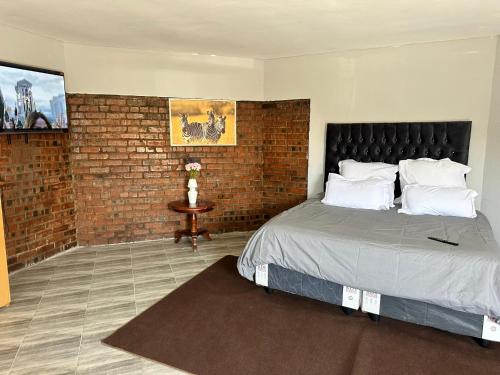 a bedroom with a bed and a brick wall at Staylax guesthouse in Harare