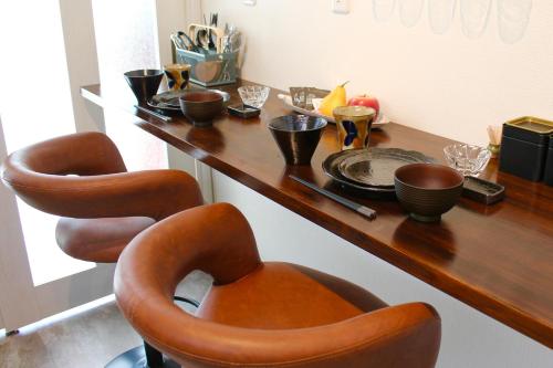 隠れ宿 藤 Private Inn Fuji - 足利駅5分の一棟貸切のお宿 في أشيكاغا: طاولة خشبية عليها كرسيين واوعية