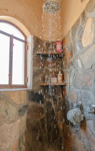 a bathroom with a stone wall with a chandelier at Master Hexagon Bedroom 180 Ocean View in Todos Santos