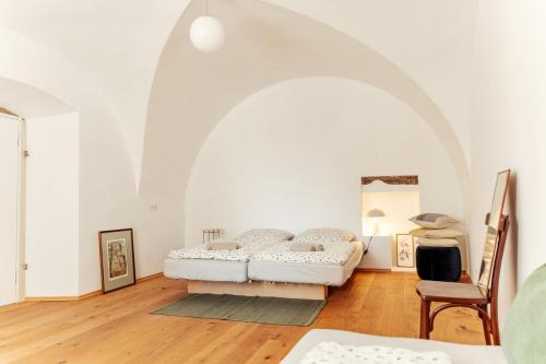 a white room with a bed and a chair at Gewölbezimmer am Hauptplatz 28 in Retz