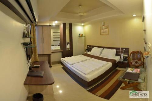a bedroom with a bed and a desk and a table at Hotel Shree Vatika in Bhopal