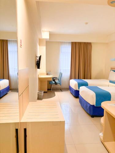 een hotelkamer met twee bedden en een bureau bij Hotel Brothers Solo in Solo