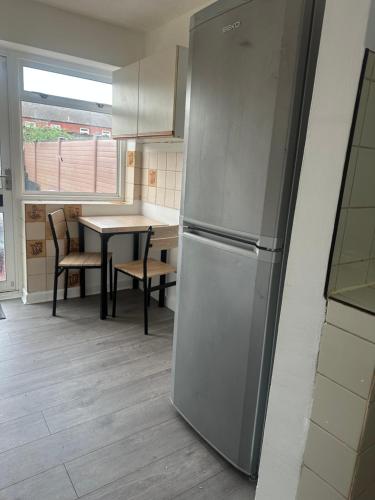 a kitchen with a stainless steel refrigerator and a table at Comfortable Rooms Near Basildon Town Centre in Basildon