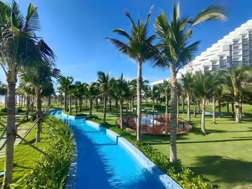 - une piscine avec des palmiers dans un complexe dans l'établissement Arena jakovi condotel, à Cam Lâm