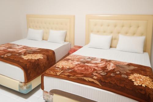 two beds sitting next to each other in a room at Luxe5 Inn Hj Hasnah Hasan in Takengon