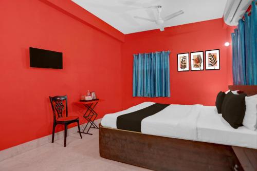 1 dormitorio con paredes rojas, 1 cama y 1 silla en Hotel O Patliputra Railway Station Formerly Rameshwaram Guest House, en Dānāpur