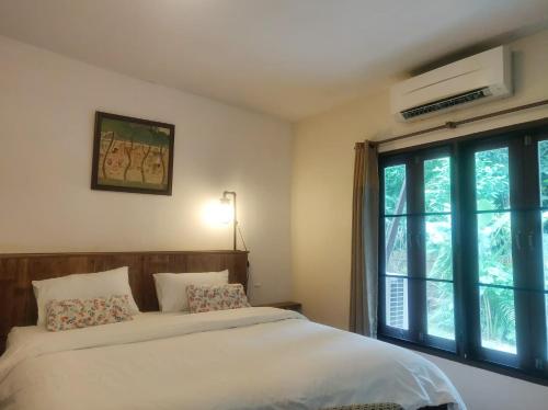 a bedroom with a bed and a large window at Fern House Retreat in Chalong 