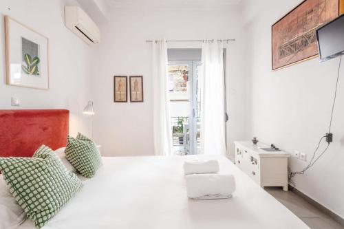 a white bedroom with a white bed with green pillows at Renovated 4 Bdr House near Acropolis - New Beds, Terrace & Green Yard in Athens