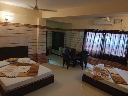 Un dormitorio con dos camas y una mesa y sillas. en Yammuna Vihaar Tourist Home, en Kollūru