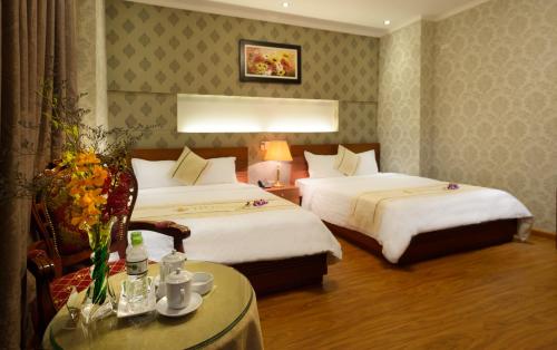 a hotel room with two beds and a table at Iris Hotel Đà Nẵng in Danang