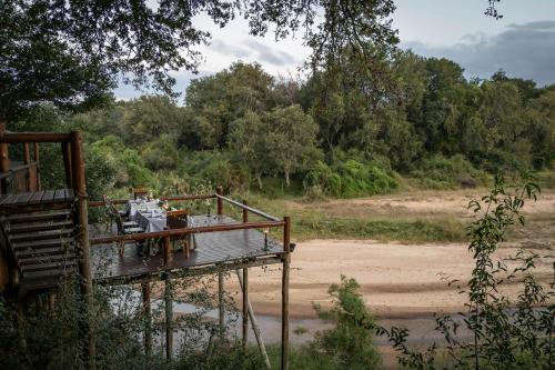 a wooden deck with a table on the side of a river at Karongwe - Kuname Safari Lodge in Hoedspruit