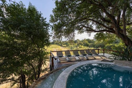 a bench with chairs sitting on top of a swimming pool at Karongwe - Kuname Safari Lodge in Hoedspruit
