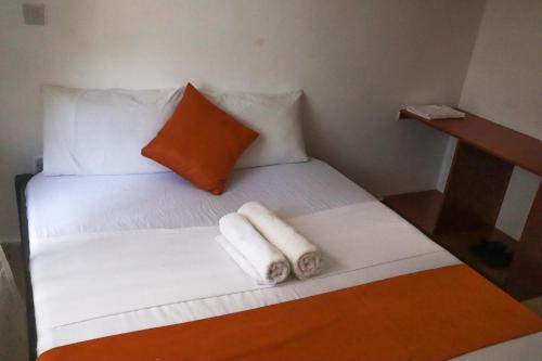 un letto bianco con due asciugamani arrotolati di Treasured Haven Stay a Ukunda