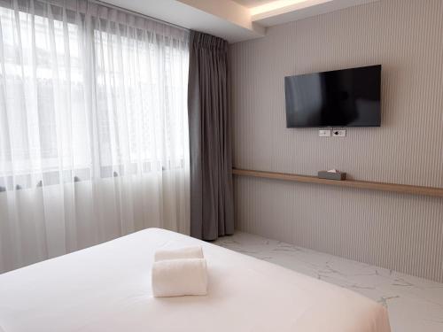a hotel room with a bed and a flat screen tv at Laoteng Boutique Hotel in Phuket Town