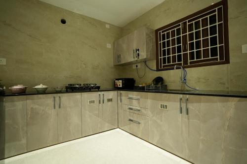 eine Küche mit weißen Schränken und einer Arbeitsplatte in der Unterkunft La Coast Beach Villa ECR in Tirupporūr