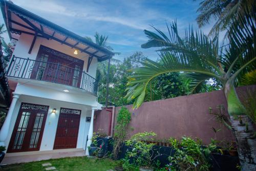 哈巴拉杜瓦Villa Aliya的白色的房子,有红色的门和栅栏