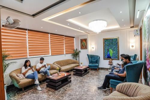 un groupe de personnes assises sur des canapés dans un salon dans l'établissement FabHotel The Grace Inn Near Galleria Market & Golf Course Road, à Gurgaon