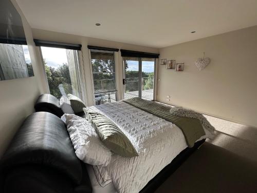 a bedroom with a bed and a leather couch at Pikes Point Beach House in Merimbula