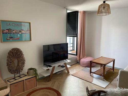 un soggiorno con TV a schermo piatto e tavolo di .Surfin' La Chaume. a La Chaume