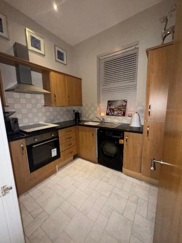 a kitchen with wooden cabinets and a dishwasher at NEWLY REFURBISHED NOV 2025 Chic City Stay In Jesmond Apartment in Jesmond