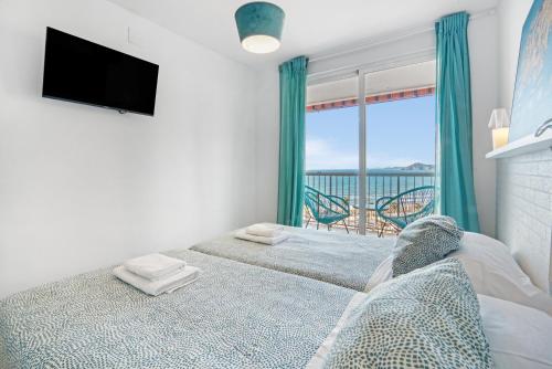 a bedroom with two beds and a tv and a balcony at Apartmento Benidorm in Benidorm