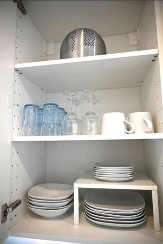 a white cabinet with plates and dishes on shelves at Paris vous aime in Le Kremlin-Bicêtre