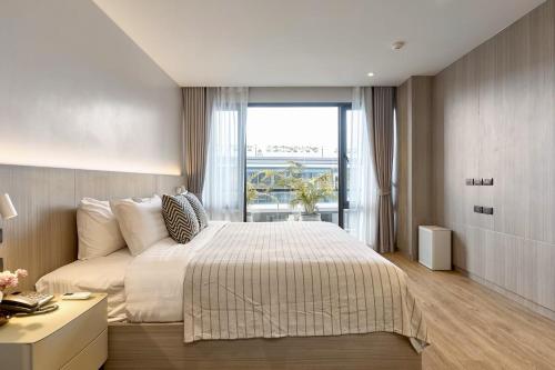 une chambre avec un grand lit et une grande fenêtre dans l'établissement Kasa Verdana, à Chiang Mai