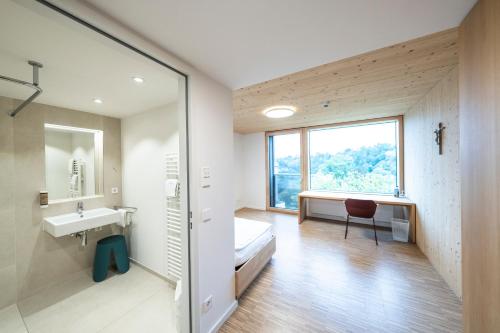 La salle de bains est pourvue d'un lavabo, d'un lit et d'une fenêtre. dans l'établissement Tagungshotel Kloster Untermarchtal, 