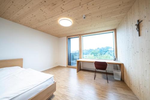une chambre avec un lit, un bureau et une fenêtre dans l'établissement Tagungshotel Kloster Untermarchtal, 