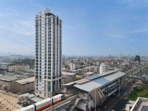 a tall white building in a city with a train station at Lumen Bangkok Srinakarin in Bangkok