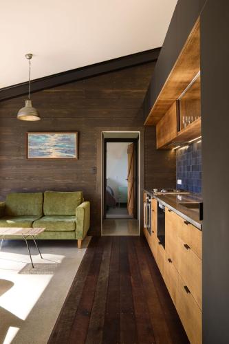 a living room with a green couch and a kitchen at Minden Retreat in Te Puna