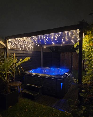 a hot tub under a pergola with lights at "Huisje op de Veluwe" met privé Jacuzzi en Bar! in Ermelo