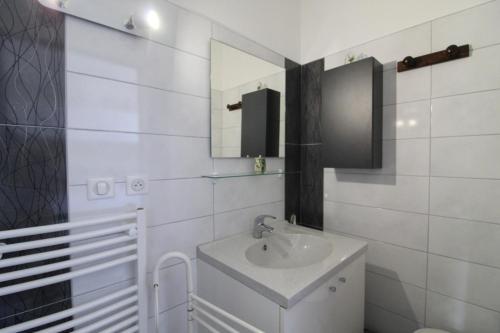 a white bathroom with a sink and a mirror at Gîte Chez Reine à ÉtivalClairefontaine Vosges Cal in Étival-Clairefontaine