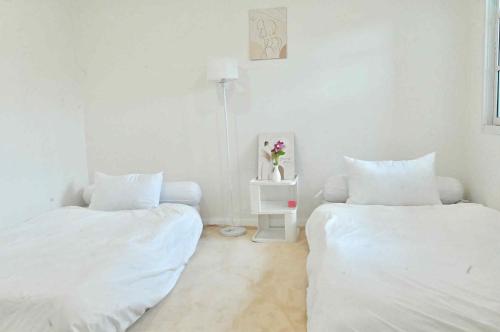 a white room with two beds and a table with flowers at บ้านเคียงดาวแม่สะเรียง 