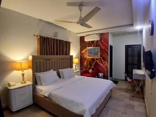 a bedroom with a large white bed with a ceiling at Seaview Lodge Guest House in Karachi
