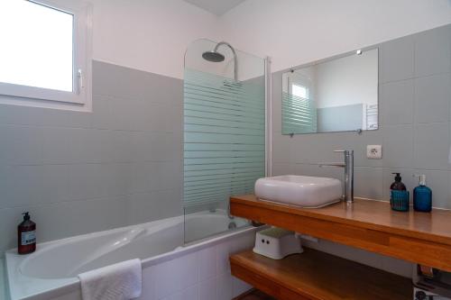 een badkamer met een wastafel, een bad en een spiegel bij Ty Kordenn - Proche Plage in Sarzeau