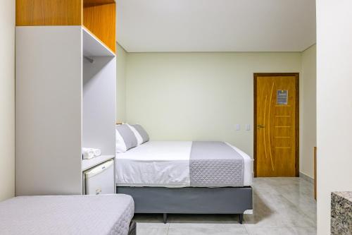 a small bedroom with two beds and a door at OYO Hotel Brisa Tropical, Brasília in Brasília