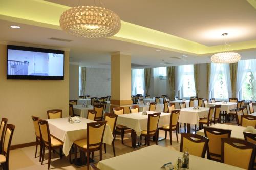 een restaurant met tafels en stoelen en een flatscreen-tv bij Uzdrowisko Połczyn Zdrój - Willa Gryf in Połczyn-Zdrój